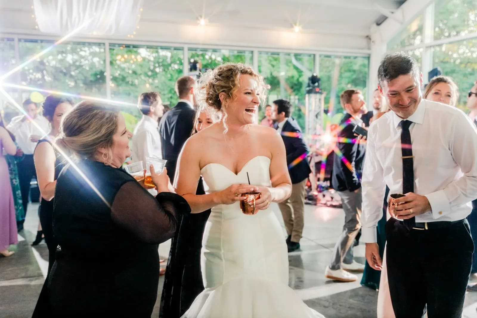 The bride laughing with a guest on the dance floor, a copper mug in her hands