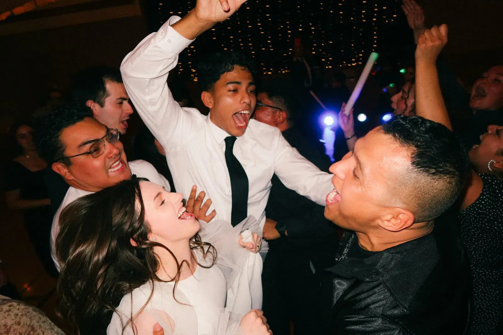 Wedding guests dancing with their arms in the air at a night reception