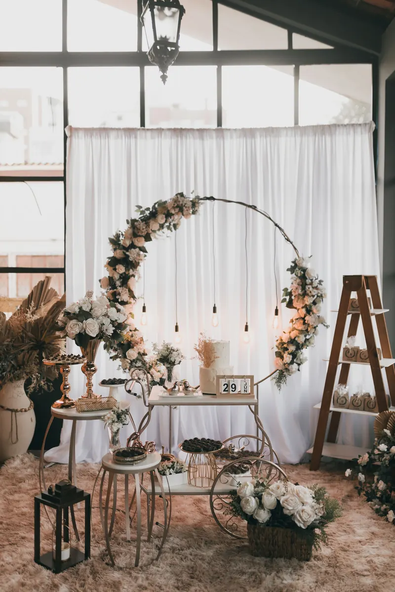 Circular floral arch behind a small decorated table with lanterns and vintage decor indoors