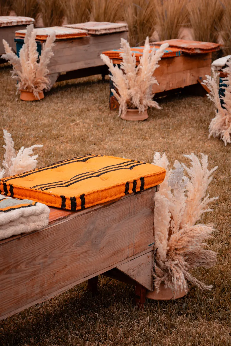 Boho outdoor wedding seating with low wooden tables, cushions, rugs and pampas grass in Marrakesh